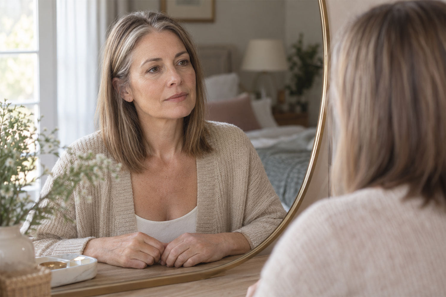 Woman with fine hair seated at a bedroom vanity in morning light