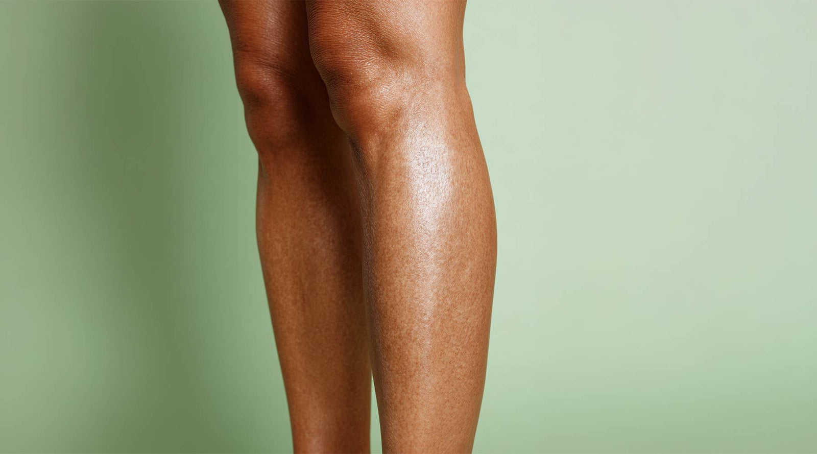 Bare legs against a sage green background