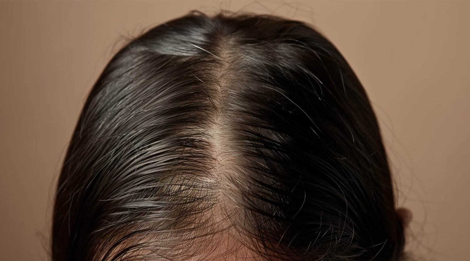 Top-down view of a part in dark brown hair with visible scalp