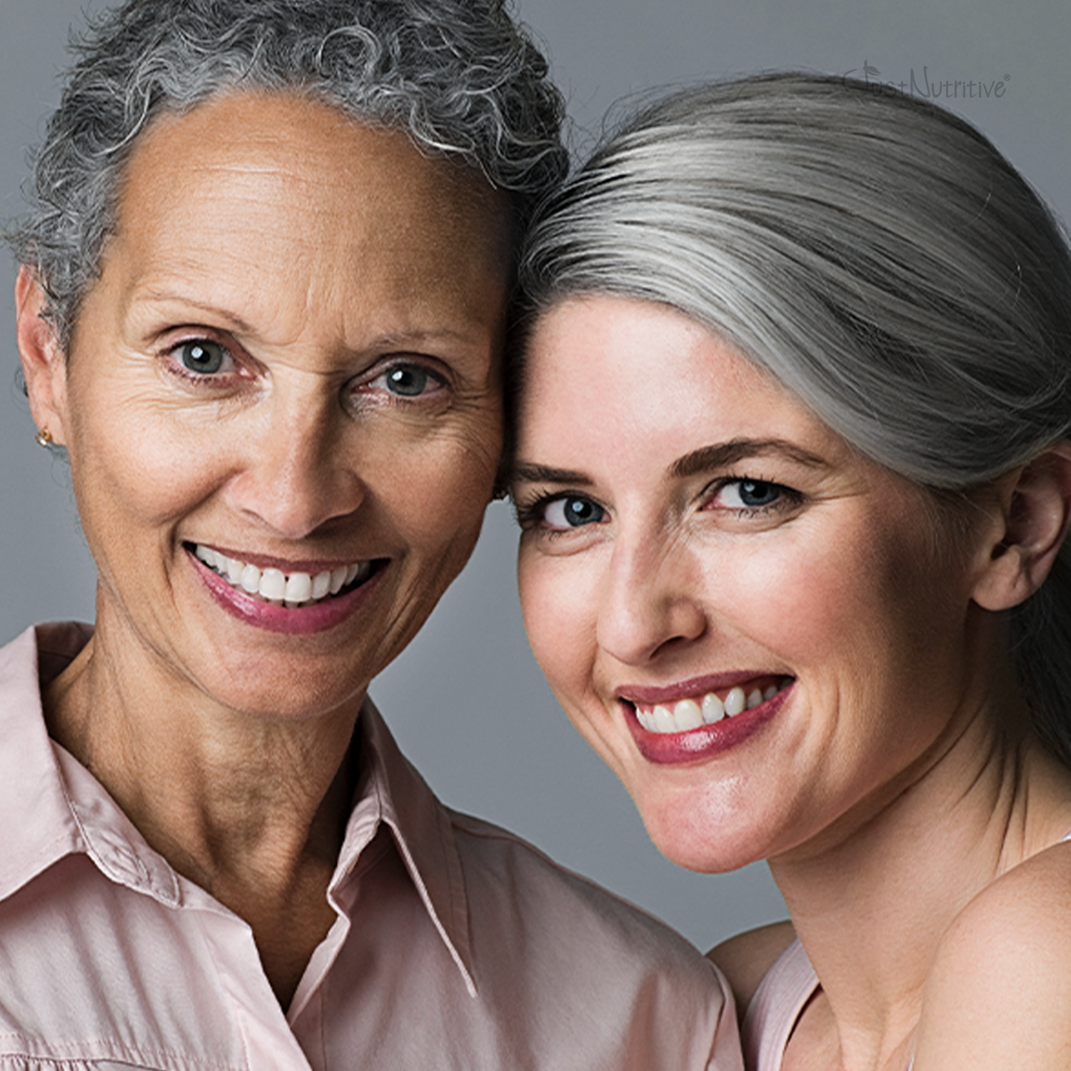 Two women with gray hair smiling against a gray background