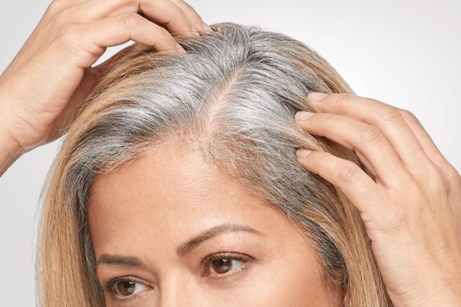Woman growing out gray hair, with silver roots and color treated lengths.