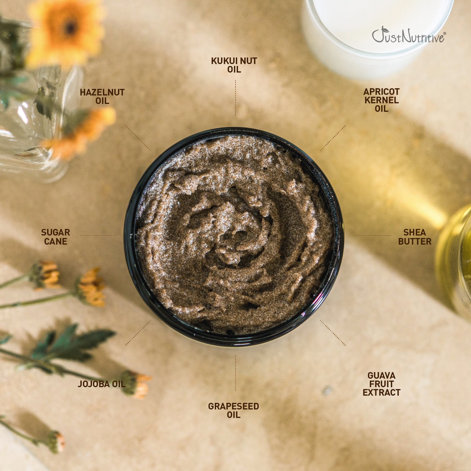 Top-down view of a bowl of brown sugar scrub with labeled ingredients on a beige surface.