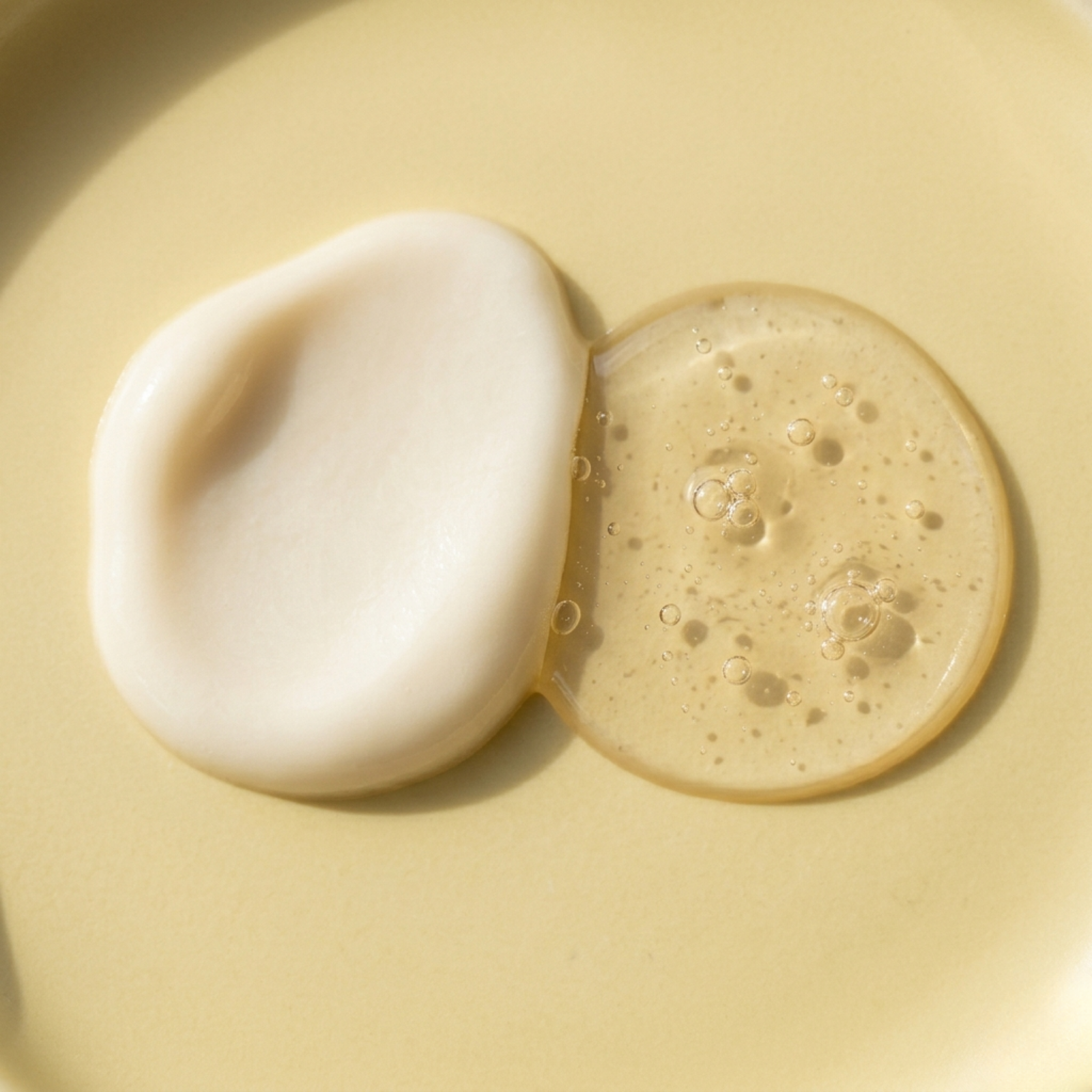 Two scoops of beige cream with bubbles on a yellow background